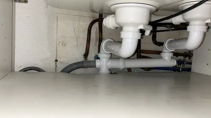 Siphons et évacuations d'un évier double sous le meuble